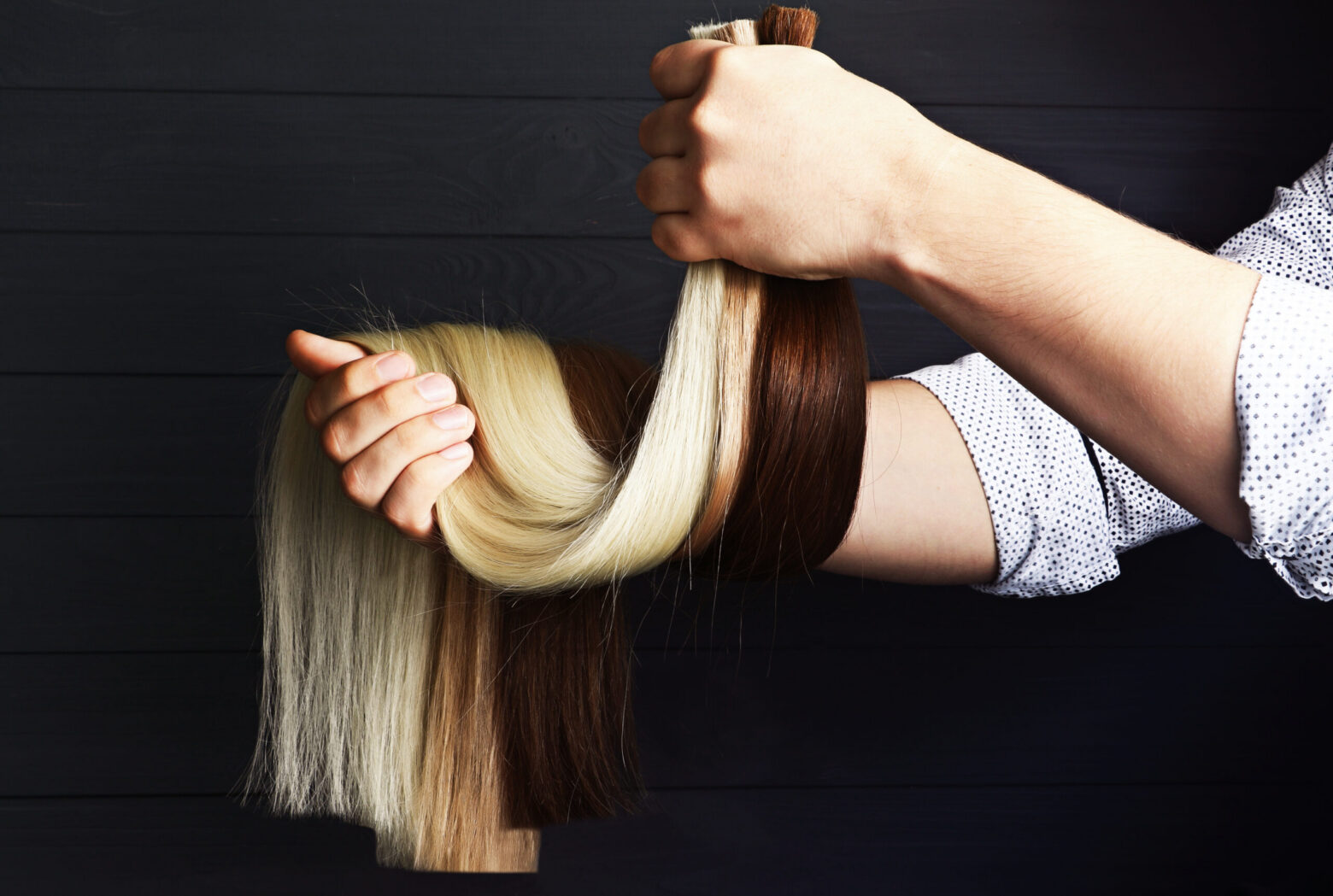 Hands holding blonde and brown hair sections