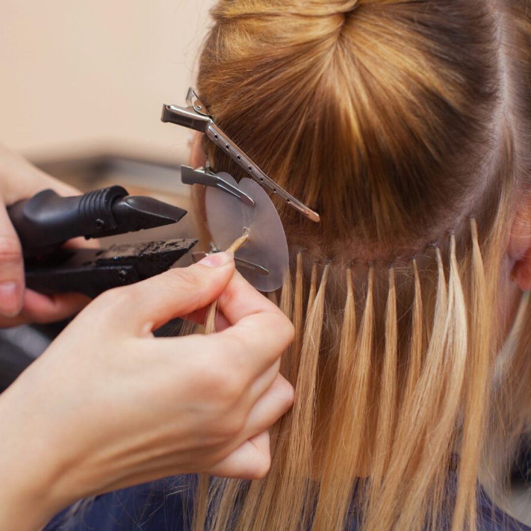 Close-up fusion hair extension installation at nape